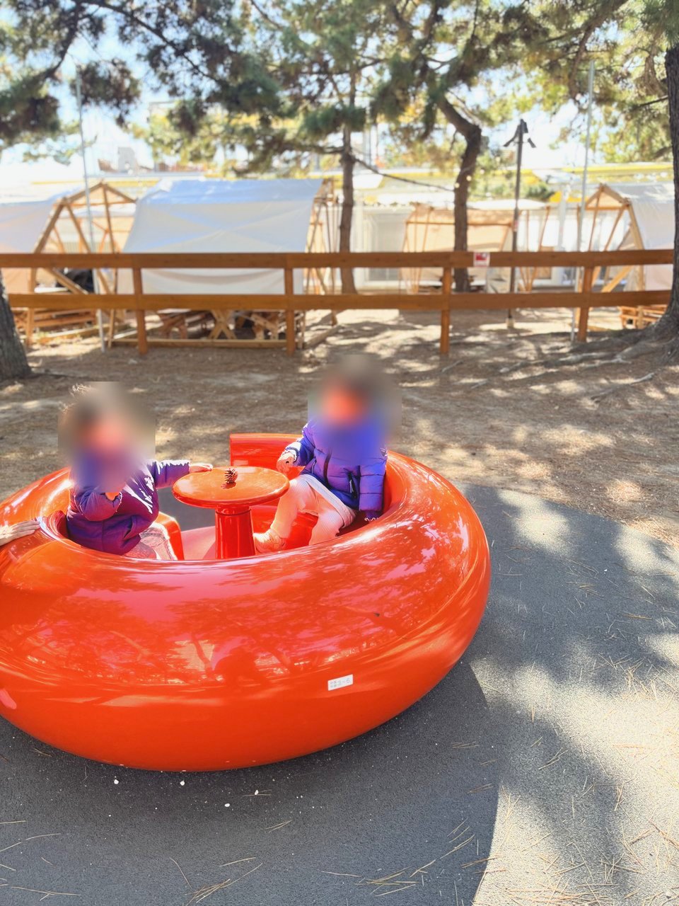 オレンジ色の丸いカップ形の遊具に乗る子どもたち