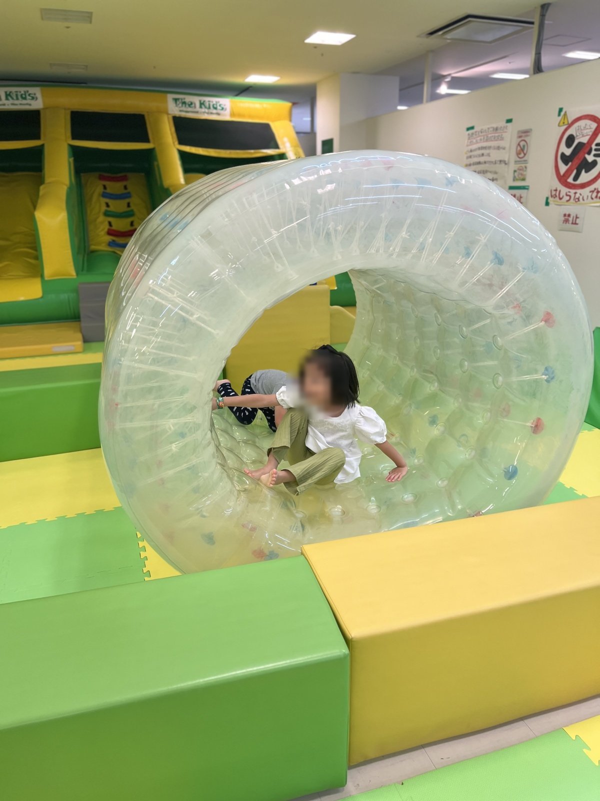 透明な回転遊具で遊ぶ子どもたち