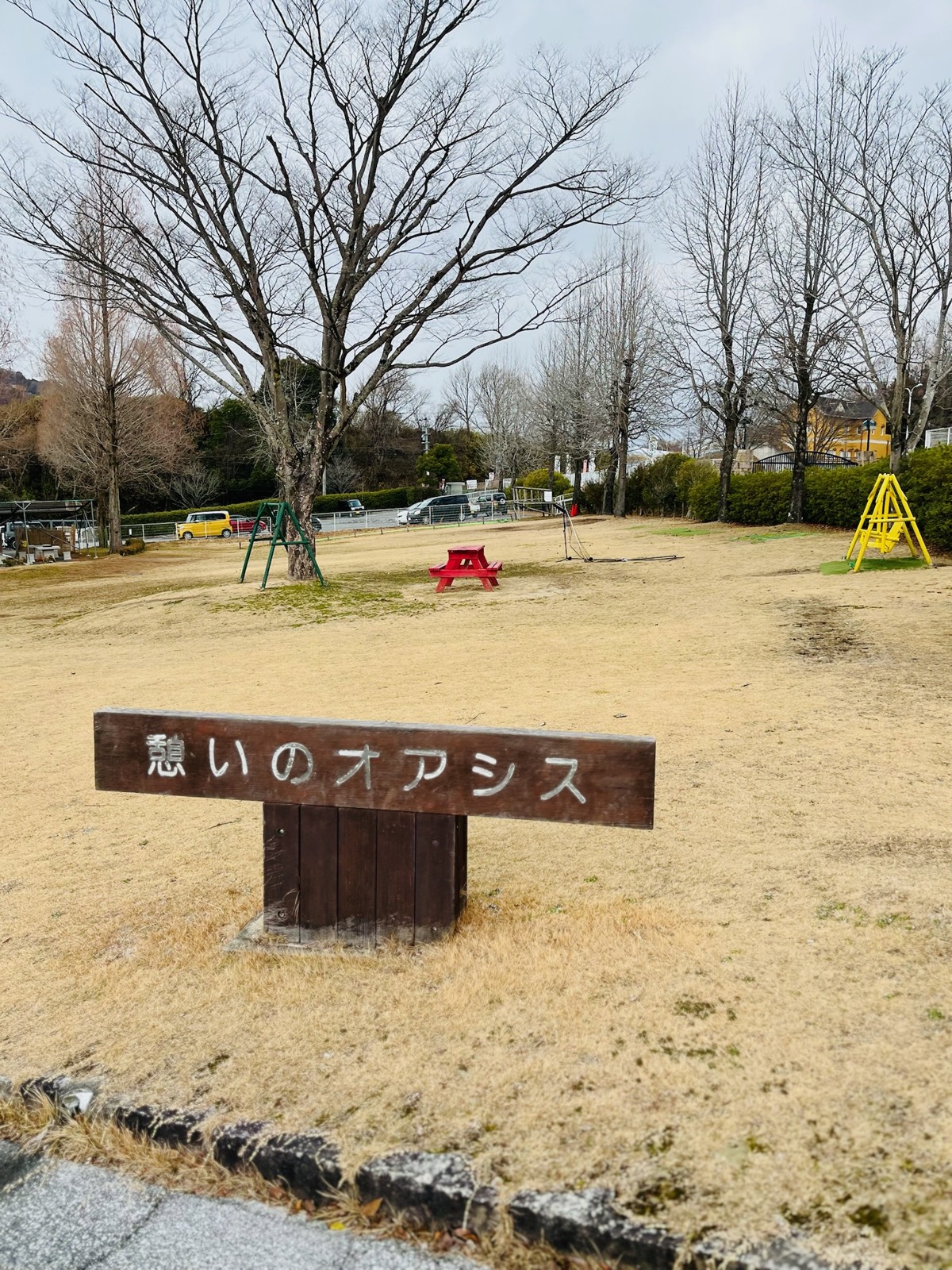 「憩いのオアシス」の木の看板がある広場