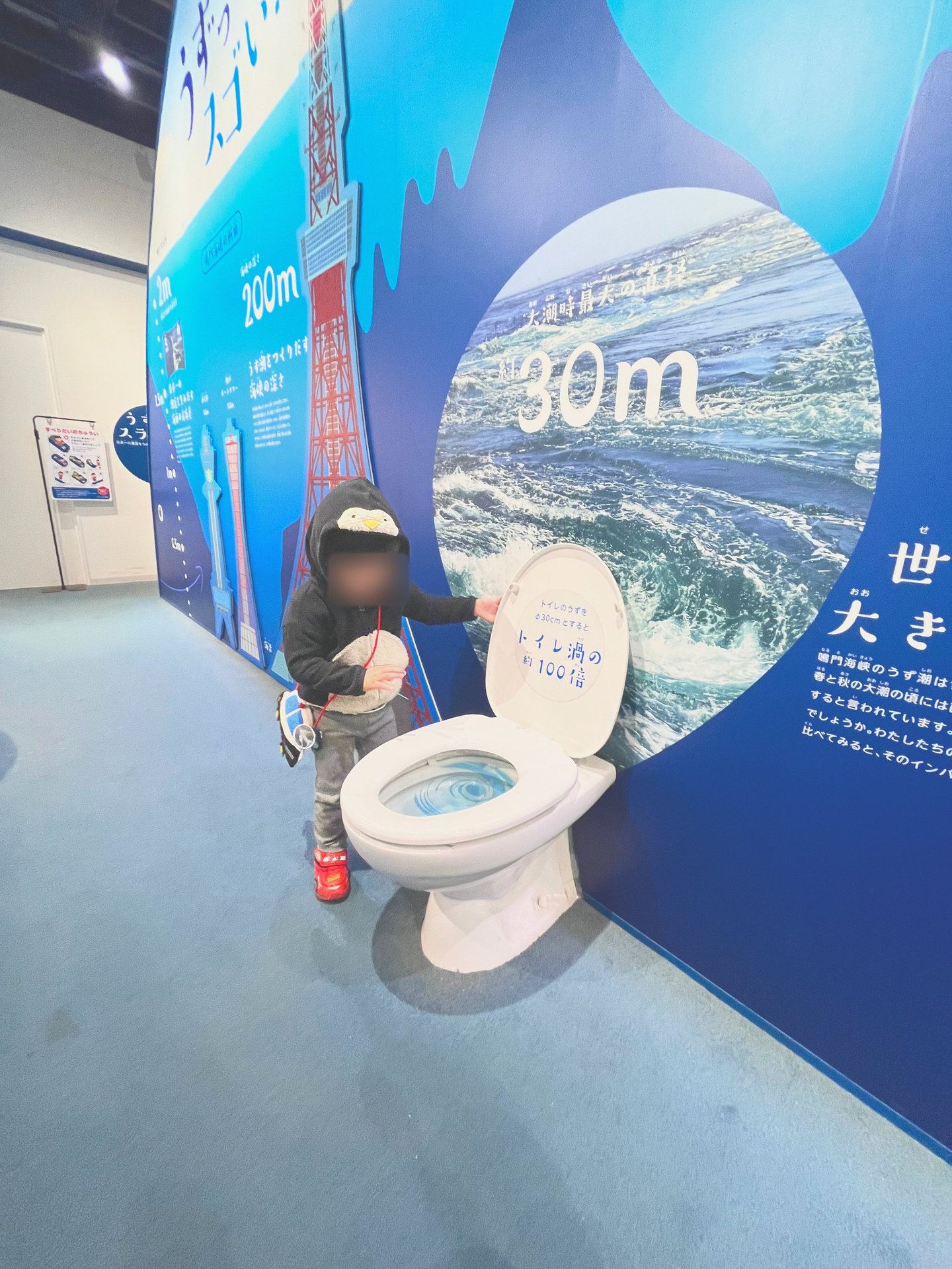 トイレの形をした展示を見ている子ども