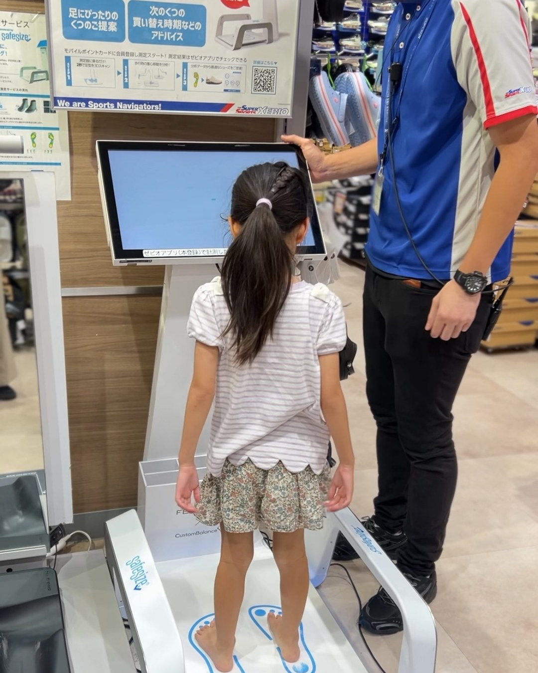 FEET AXISの測定台に素足で立つ子どもと、そばで見守るスタッフ