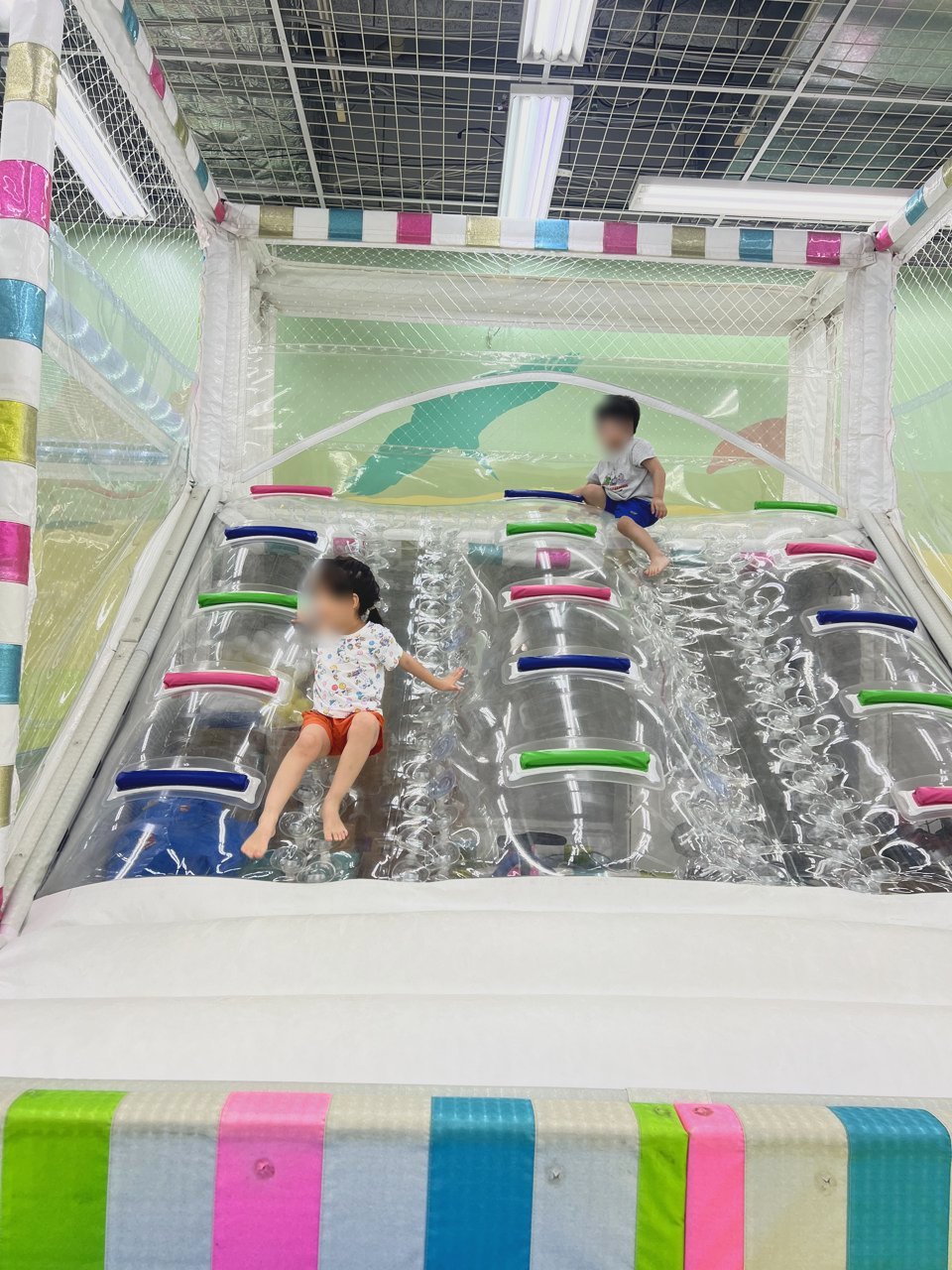 透明なすべり台をすべる子どもたち